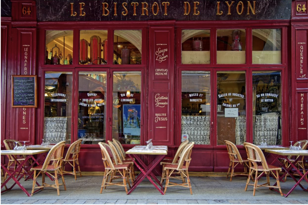 A bistro in Lyon with empty cafe tables and chairs outside the red painted eatery
